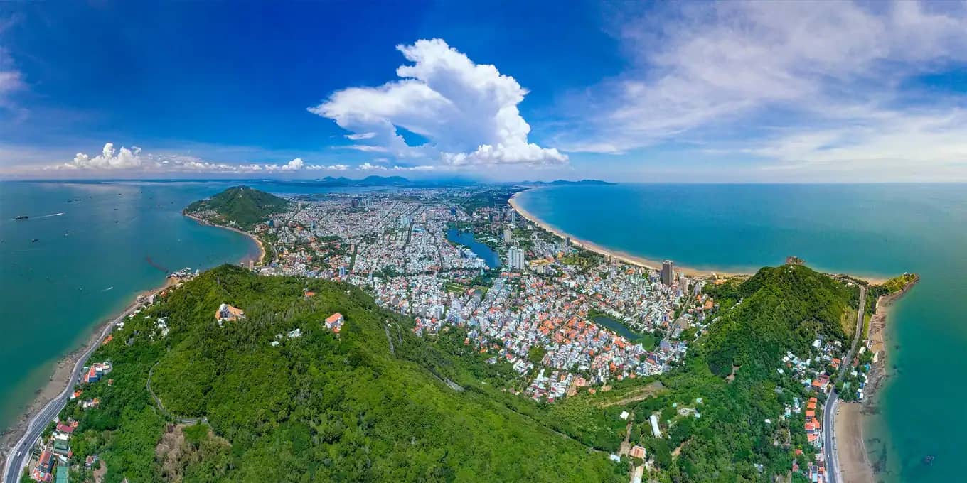 Bana city aerial view showing lush green hills, urban development, and coastline in a picturesque coastal cityscape.